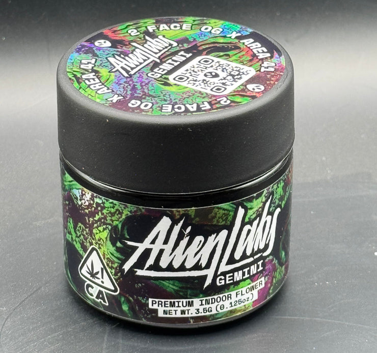 This image features the " Alien labs Gemini " product, presented in a small container with a black lid. The label on the container is vibrant and detailed, with a space-themed design including illustrations of planets and a rocket.